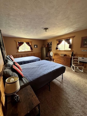 A room with two beds, a wooden dresser, a desk, and a chair.