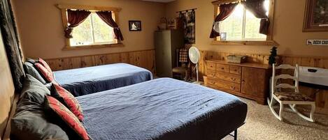 A room with two beds, a wooden dresser, a desk, and a chair.