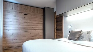 Et soveværelse med seng, træskab og loftlampe.