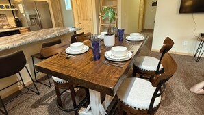 A dining area with a wooden table set for six, surrounded by chairs with white cushions. - Fantastic cabin retreat for 6 with 2 bathrooms and AC in cozy Heber-Overgaard (Heber-Overgaard)