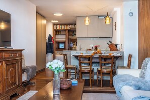 A modern kitchen with wooden cabinets, a dining area with a table and chairs, and a living room with a sofa and a coffee table.