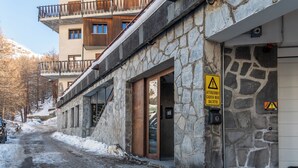 Un edificio in pietra con un balcone in metallo, un cartello di avvertimento e una strada ricoperta di neve.