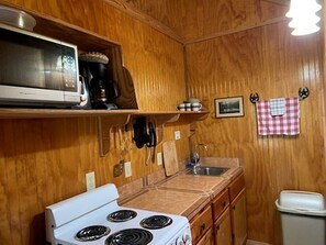 Una cocina compacta con estufa, microondas y fregadero.