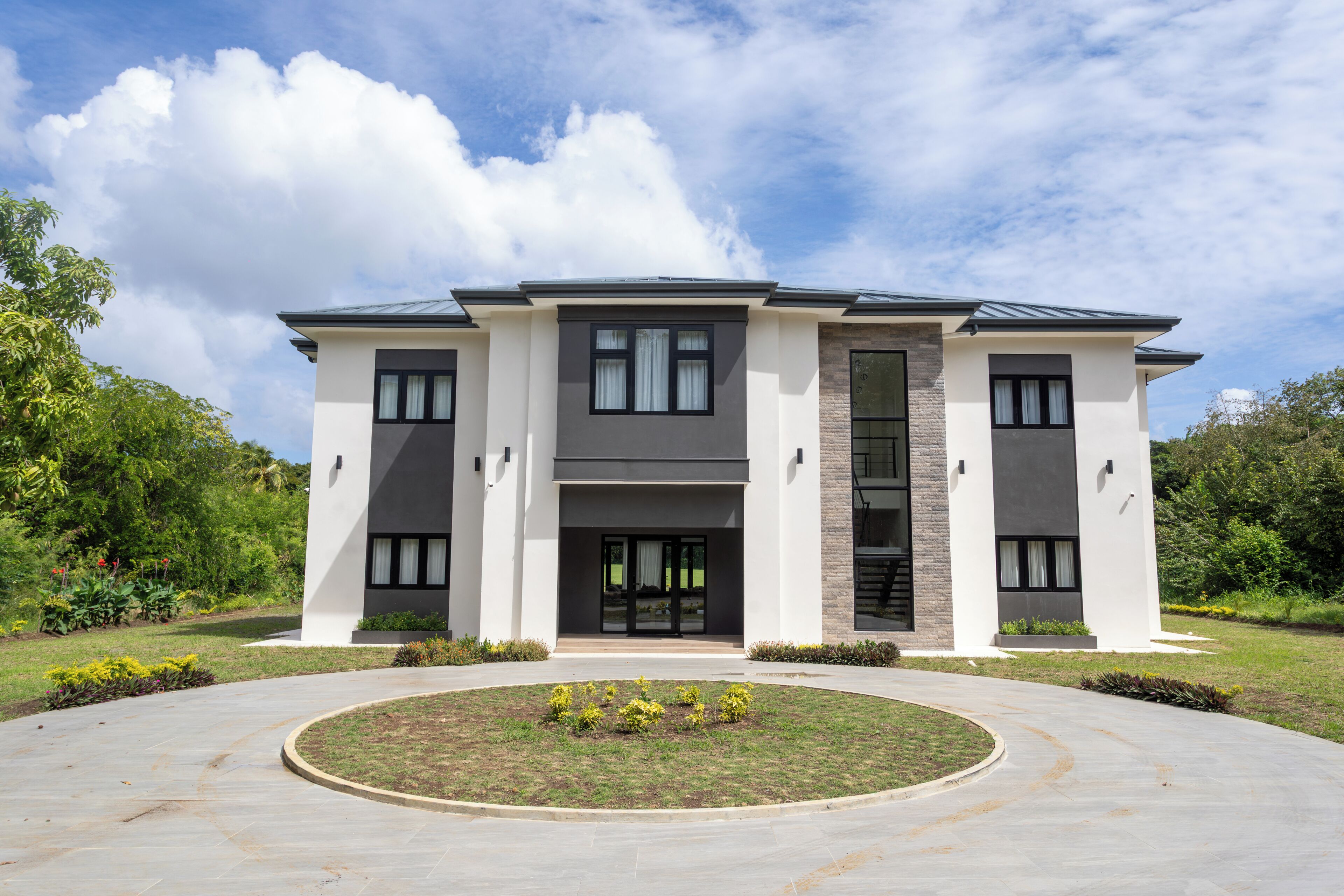 Une maison moderne à deux étages, dotée d’une façade symétrique, de grandes fenêtres et d’une entrée centrale.