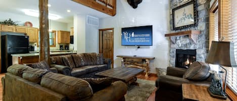 A spacious living room with a large sectional sofa, a fireplace, a stone wall, and a mounted buffalo head.