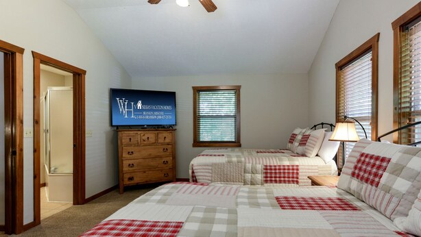 A bedroom with two beds, a dresser, a television, and a window with blinds. - Spacious Cabin with Indoor and Outdoor Swimming Pool in Branson, Missouri (Branson)