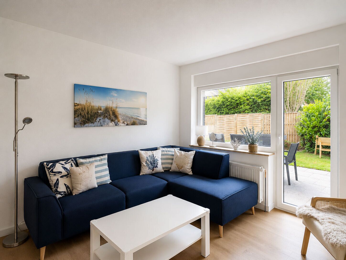 A modern living room with a blue sectional sofa, a white coffee table, and a large window with a view of a garden.