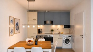 Een kleine keuken met een eettafel, stoelen, een wasmachine en een magnetron.