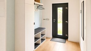 Een gang met een witte kast, een zwarte deur en een lichtgekleurde muur.