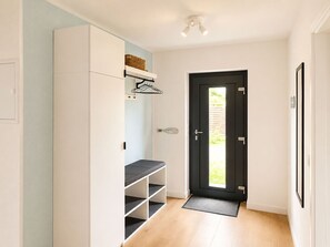 A hallway with a white wardrobe, a black door, and a light-colored wall. - Kellenquartier – Anker 8 | Newly renovated, family-friendly, with a garden (Kellenhusen (Ostsee))