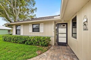 A single-story house with a front door, a small porch, and a well-maintained lawn.