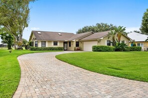 A residential house with a paved driveway, a garage, and a well-maintained lawn.