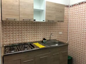 A kitchen with a gas stove, stainless steel sink, wooden cabinets, and patterned wall tiles. - Quiet 3-bedroom apartment in a central location in Cali (Cali)