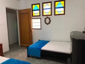 A room with a bed, a wardrobe, a small table, and a wall with four stained glass windows. - Quiet 3-bedroom apartment in a central location in Cali (Cali)