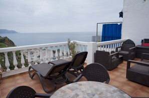 A terrace with outdoor furniture, a view of the sea, and a white balustrade. - Casa Miles - One Bedroom Apartment, Sleeps 2 (Nerja)