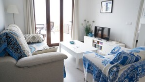 Una sala de estar con un sofá, una mesa de centro, un televisor y una estantería.