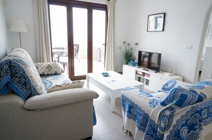 Ein Wohnzimmer mit einer Couch, einem Couchtisch, einem Fernseher und einem Bücherregal.