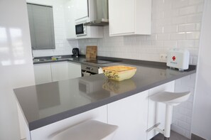 Eine moderne Küche mit weißen Schränken, einer grauen Arbeitsplatte, einer Mikrowelle, einem Toaster und einem Schneidebrett.