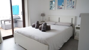 Un dormitorio con cama, mesita de noche, lámpara y vistas al exterior.