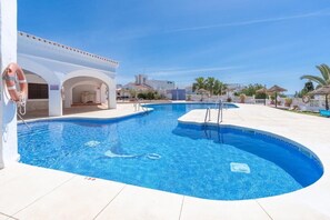 Ein Swimmingpool mit klarem, blauem Wasser, einem Rettungsring und einem weißen Gebäude mit Bögen.