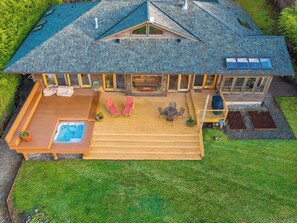 Een tweelaags huis met een houten terras, een jacuzzi en een overdekte patio.
