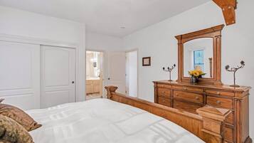 A bedroom with a bed, dresser, mirror, and a door leading to a bathroom.