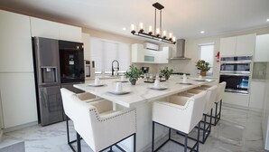 Een moderne keuken met een centraal eiland, roestvrijstalen apparatuur en witte kasten.