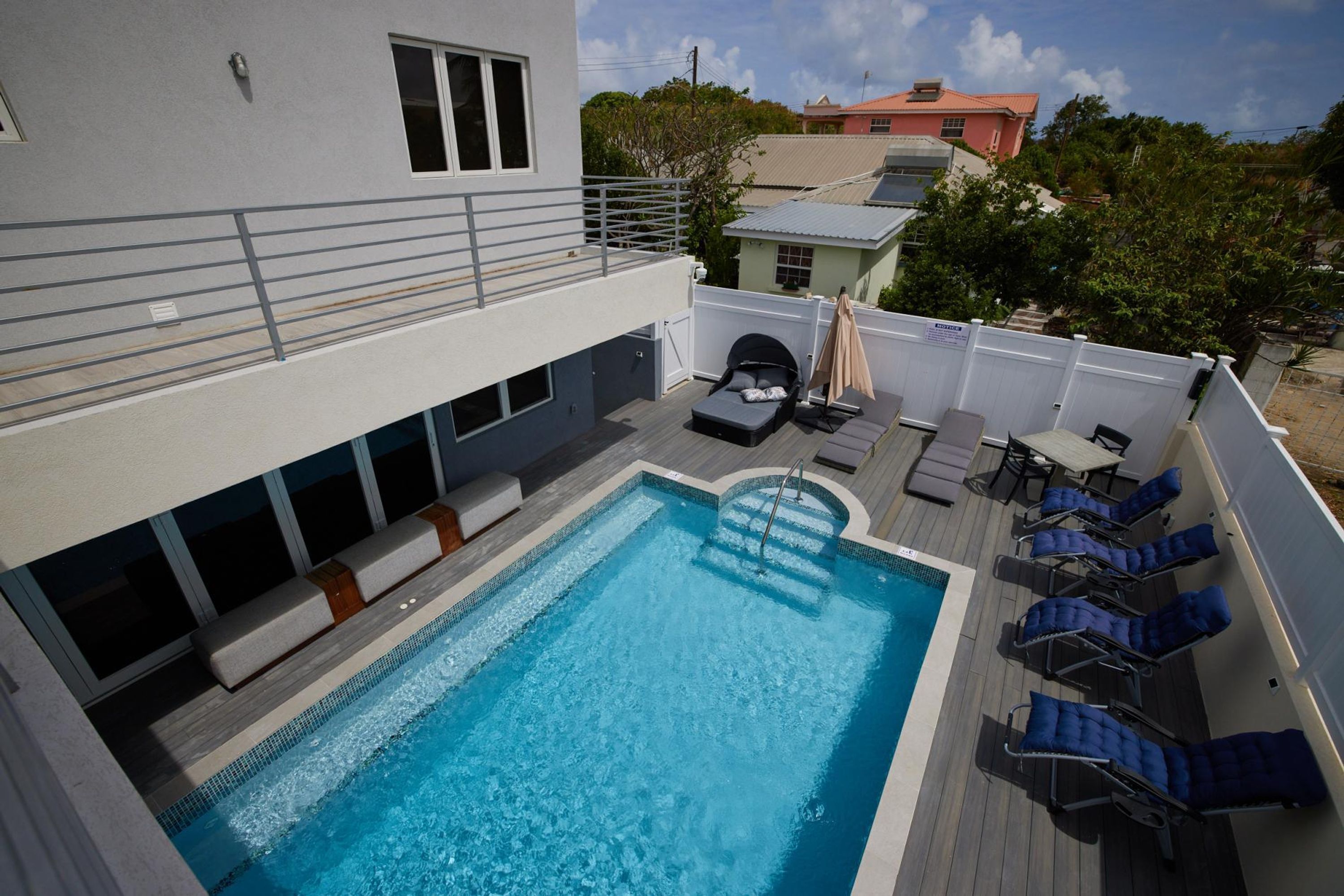 A rooftop pool with lounge chairs, a sun lounger, and a small seating area.