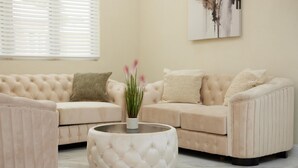 Een beige modulaire bank met een glazen salontafel en een vaas met groene planten.