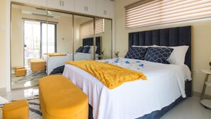 A bedroom with a bed, a bench, a wardrobe, and a mirror. - Aurelia- 1BR Luxury Beachfront Condo (St. Ann's Bay)