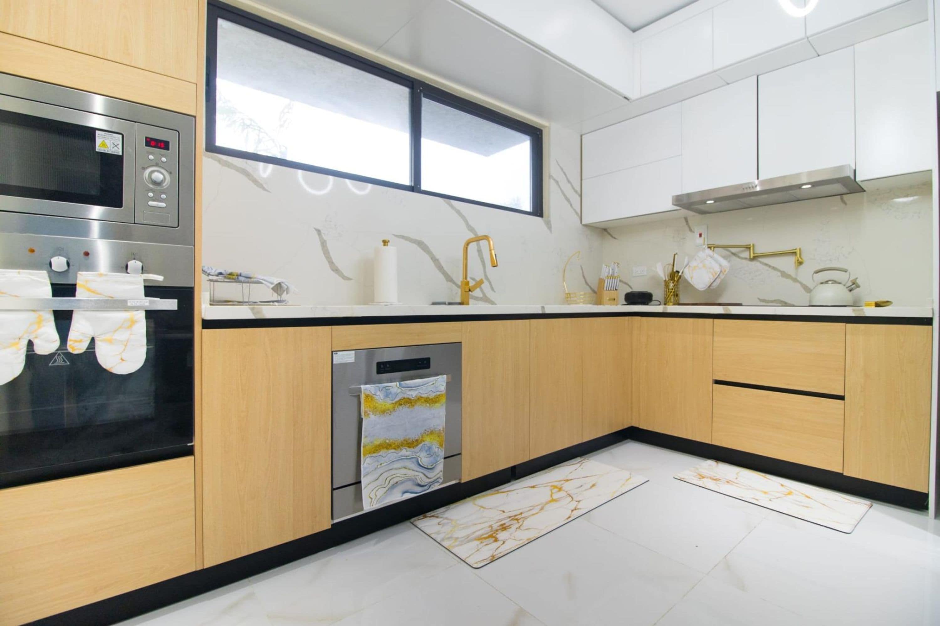 A modern kitchen with a built-in oven, a dishwasher, and a window above the sink.
