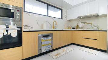A modern kitchen with a built-in oven, a dishwasher, and a window above the sink.
