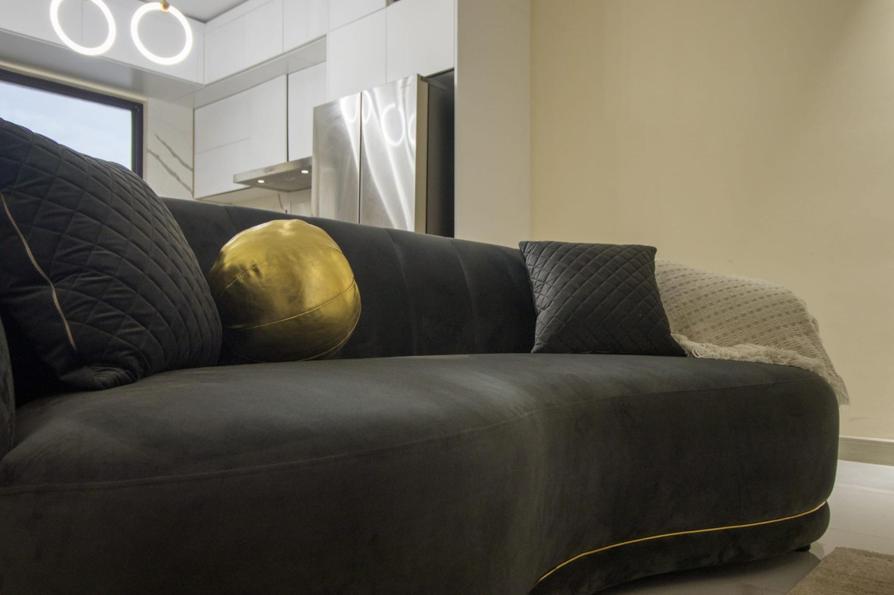 A modern living room with a dark-colored sofa, a gold accent pillow, and a white throw blanket.