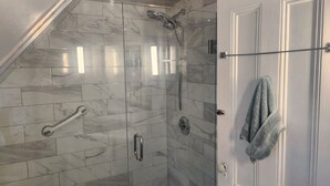 Eine Dusche mit Glastür, einem Handtuchhalter und einer Wand mit Marmorfliesen.