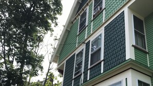 Ein mehrstöckiges Gebäude mit grüner Fassade und weißem Zierdekor, mit großen Fenstern und einer sichtbaren Klimaanlage.