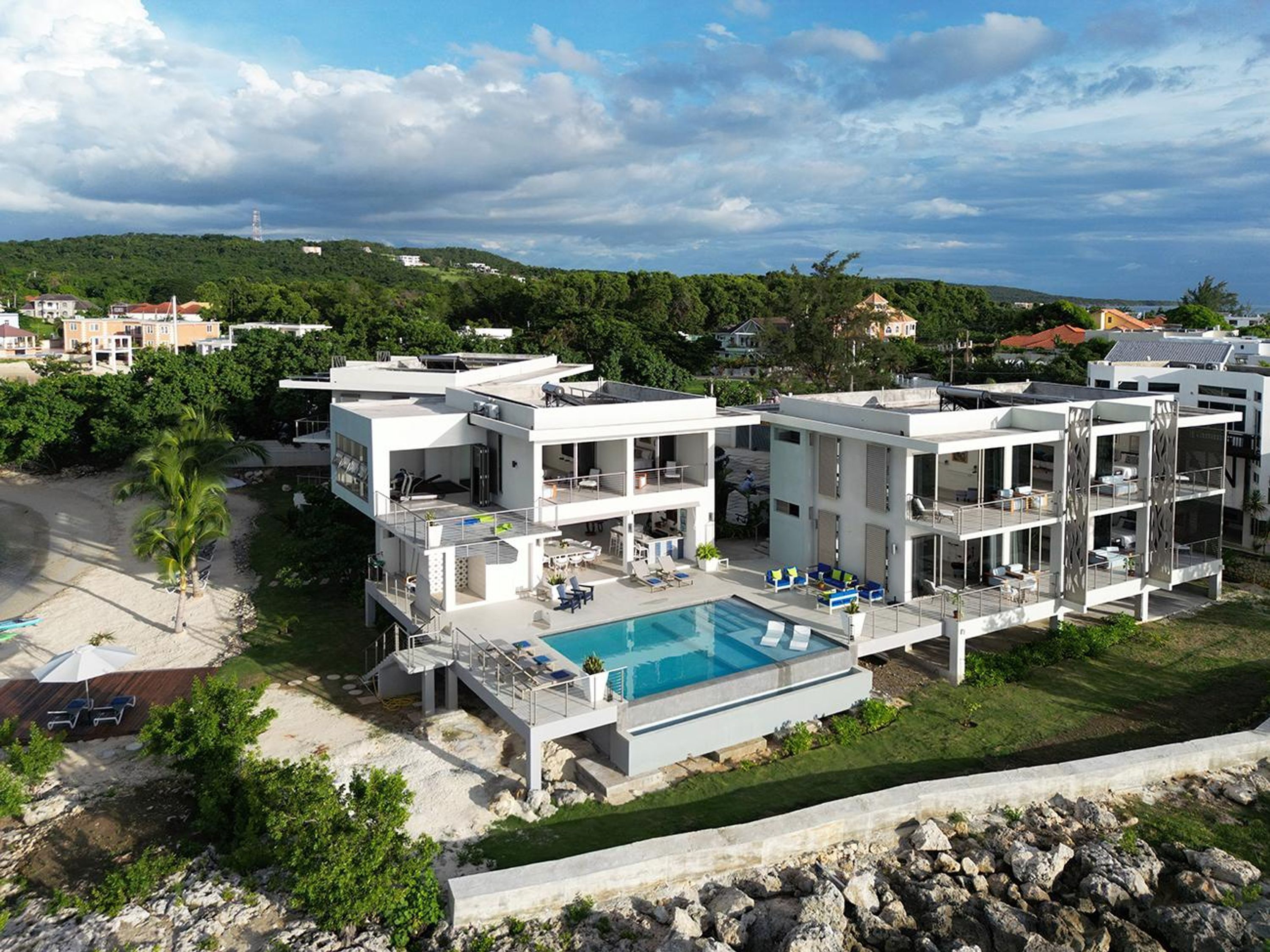 A modern multi-story hotel with a rooftop pool and a view of the surrounding landscape.