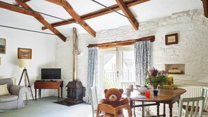 Een gezellige woonkamer met een open haard, een televisie en een eethoek met een tafel gedekt voor twee.