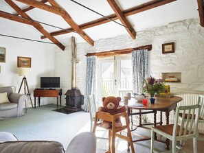 A cozy living room with a fireplace, a television, and a dining area with a table set for two. - The Forge Trevadlock Manor Cornwall (Congdon's Shop)