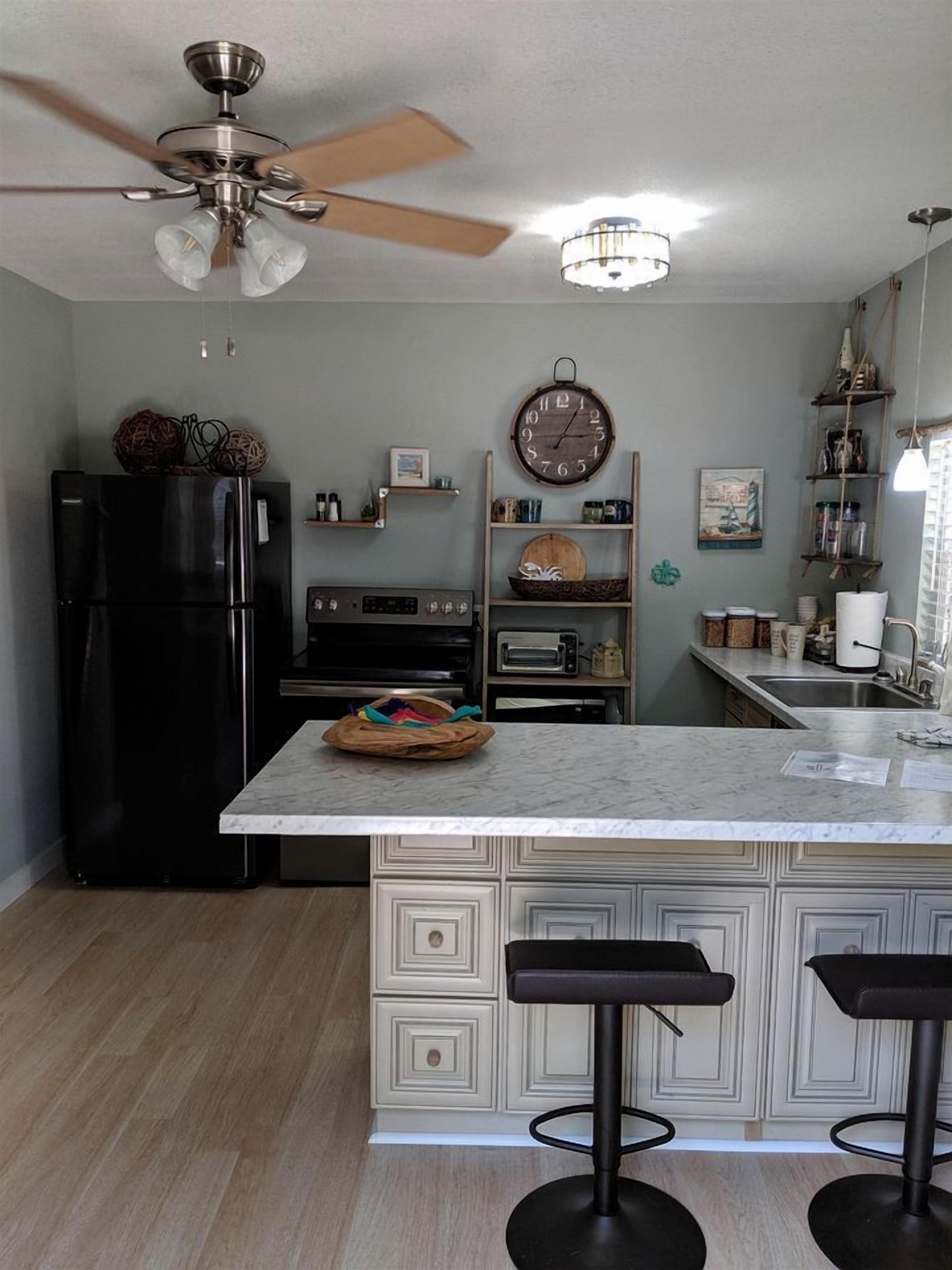 Una cocina con refrigerador, horno, tostadora y un reloj en la pared.