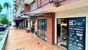 A storefront with a glass facade, a brick building, and a tiled sidewalk. - Apartamento en Pinares con piscina (Pereira)