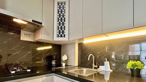 A modern kitchen with a black marble countertop, stainless steel sink, and a built-in dishwasher. - Apartamento en Pinares con piscina (Pereira)