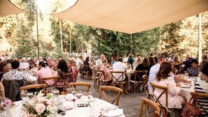 An outdoor dining area with round tables, chairs, and a canopy.