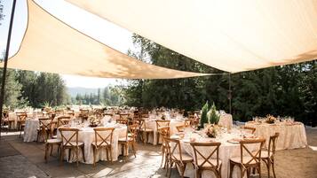 An outdoor event space with round tables, chairs, and a canopy.