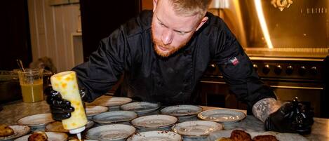 A chef preparing food in a kitchen with stainless steel appliances and a marble countertop.