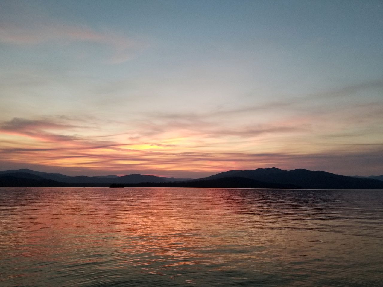 A calm body of water reflecting a sunset sky.