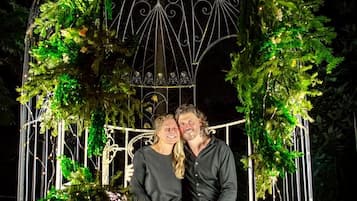 Una pareja sentada bajo un pabellón decorado con follaje y velas.