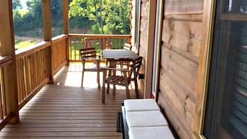 A wooden deck with a bench, a table, and chairs.