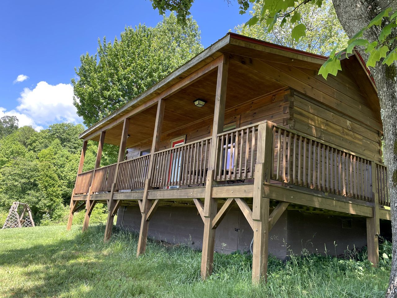 Eine Holzhütte mit einem Balkon, umgeben von viel Grün.