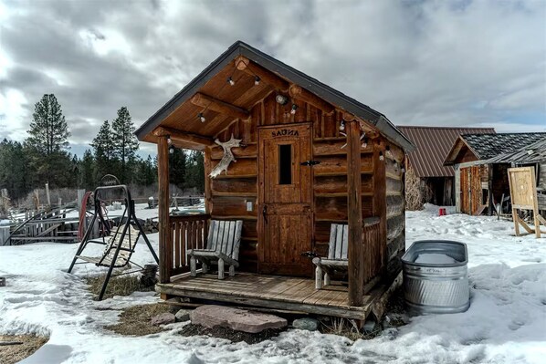 A wooden cabin with a porch, a bench, and a sled.