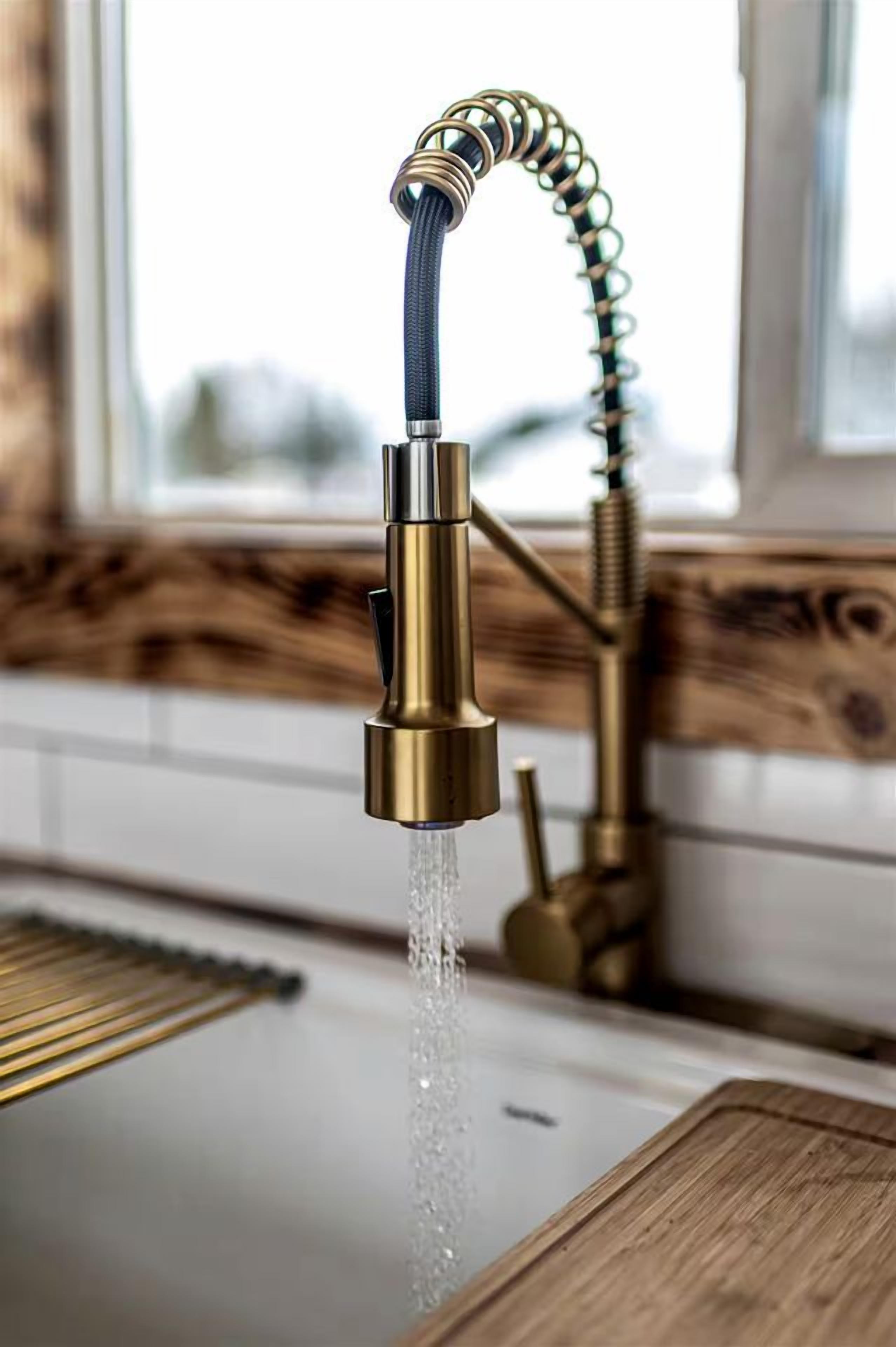 A kitchen with a brass faucet, a wooden countertop, and a window in the background.